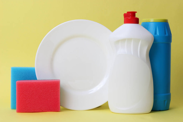 Spülmittel, Schwämme, Teller auf farbigem Hintergrund. Hausarbeit, Geschirrspülen - Foto, Bild