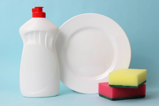 жидкость для мытья посуды, губки, пластины на цветном фоне. домашние дела, мытье посуды
 - Фото, изображение