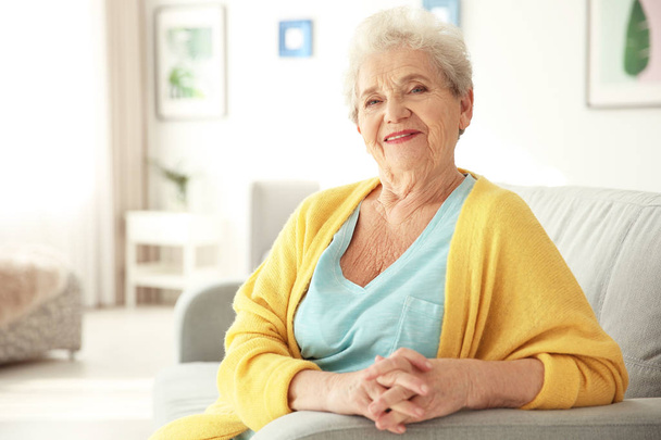 Elderly woman sitting on couch in living room - Photo, image