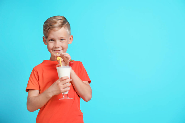 Little boy with glass of milk shake on color background - Foto, afbeelding