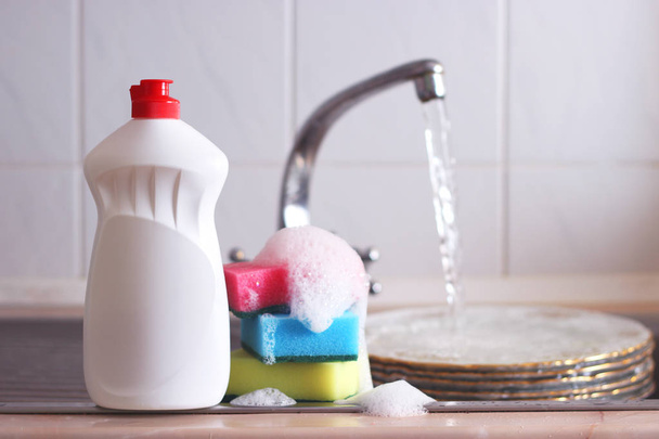 Waschmittel und Schwämme auf dem ausgewaschenen Hintergrund der Spüle. - Foto, Bild