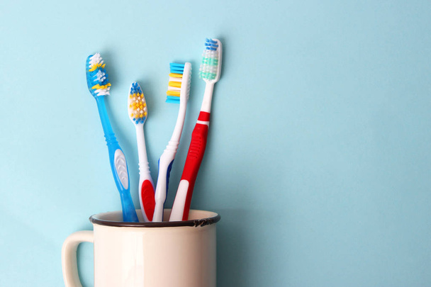 οδοντόβουρτσες σε ένα ποτήρι σε έγχρωμο φόντο. στοματική υγεία, βουρτσίζετε τα δόντια σας, υγιή δόντια - Φωτογραφία, εικόνα