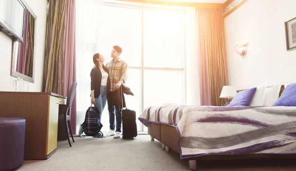 Νεαρό ζευγάρι έφτασε στο δωμάτιο του ξενοδοχείου για μήνα του μέλιτος - Φωτογραφία, εικόνα