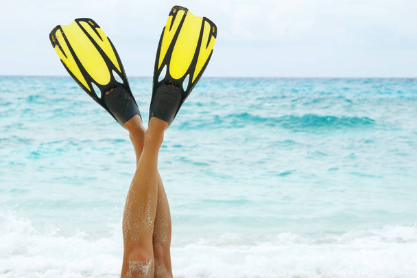 Cropped image of female legs in flippers on beach - Foto, afbeelding