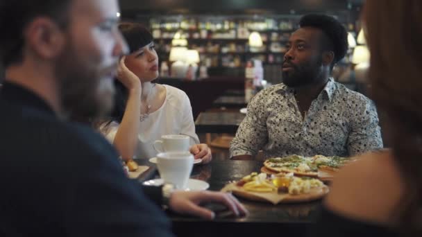 junger Mann und Mädchen sitzen an einem Tisch in einem Café oder Restaurant und unterhalten sich. - Filmmaterial, Video