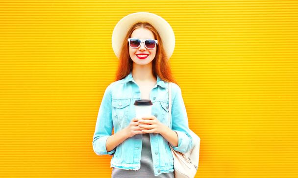 Happy stylish girl with coffee cup on a orange background - Zdjęcie, obraz