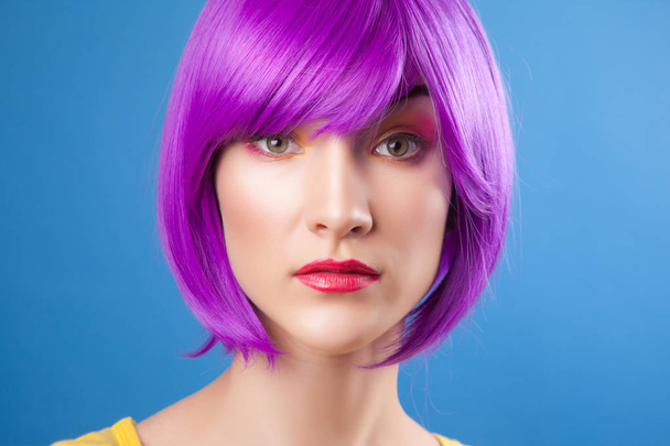 beautiful woman wearing colorful wig against blue background - Foto, imagen