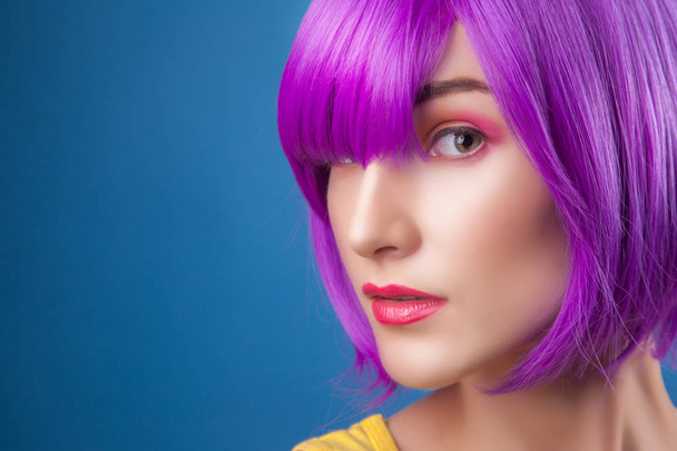 beautiful woman wearing colorful wig against blue background - Photo, Image