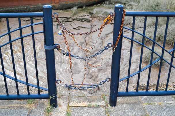 As extremidades de dois trilhos de vedação azul com os postes conectados por cadeias azuis e laranja
 - Foto, Imagem