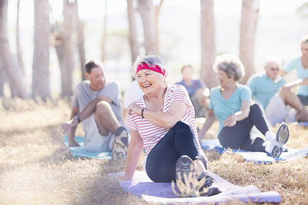 Glimlachend senior vrouw praktizerende yoga in zonnig park - Foto, afbeelding