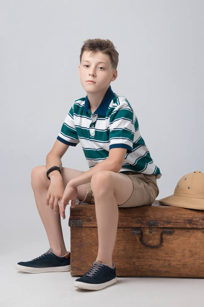 the boy is sitting on a suitcase while waiting - Valokuva, kuva