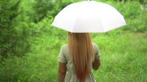 Mujer caminando mano sosteniendo paraguas blanco bajo la lluvia
  - Metraje, vídeo