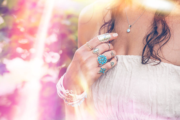 Close-up van jonge vrouw hand met veel boho stijl jewrly, ringen en armbanden buiten zomer dag lichte lekkage - Foto, afbeelding