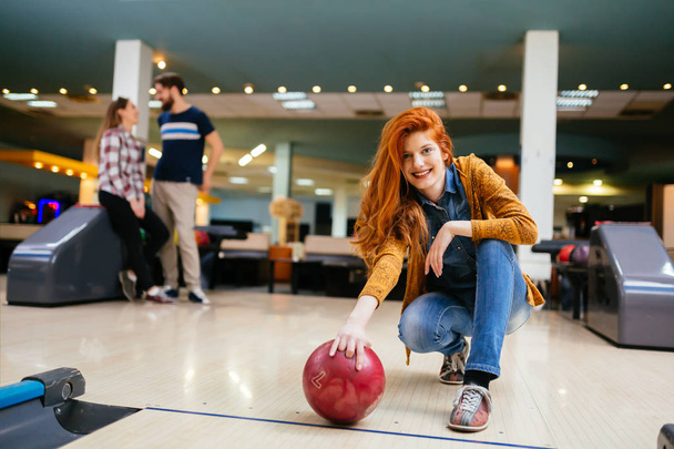 Beautiful woman bowling with friends getting ready to throw ball - Fotografie, Obrázek
