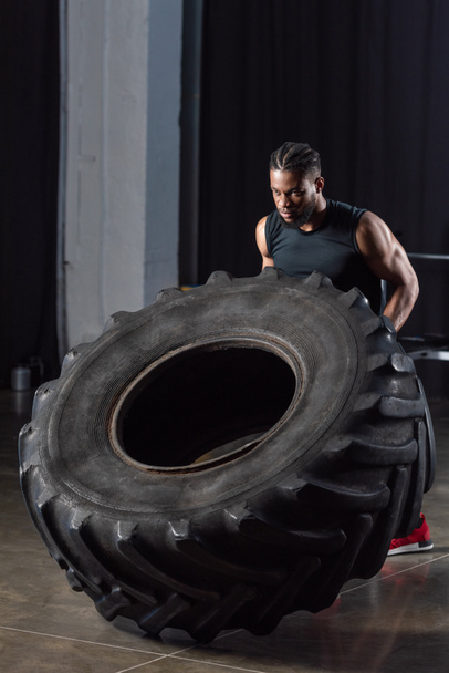 handsome muscular young african american sportsman training with tire - Foto, imagen