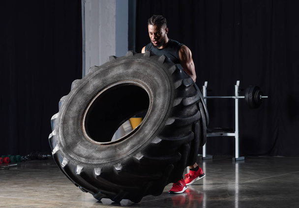 muscular young african american sportsman exercising with tire   - Fotoğraf, Görsel