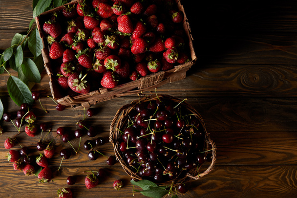 vista superior de cerezas y fresas en cesta y caja sobre mesa de madera
 - Foto, Imagen