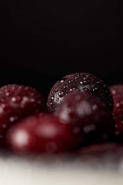 крупным планом свежие красные вишни, покрытые капельками воды, выделенные на черном
 - Фото, изображение
