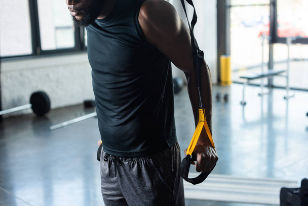 przycięte strzał mięśni młody człowiek african american szkolenia z paskami fitness w siłowni - Zdjęcie, obraz
