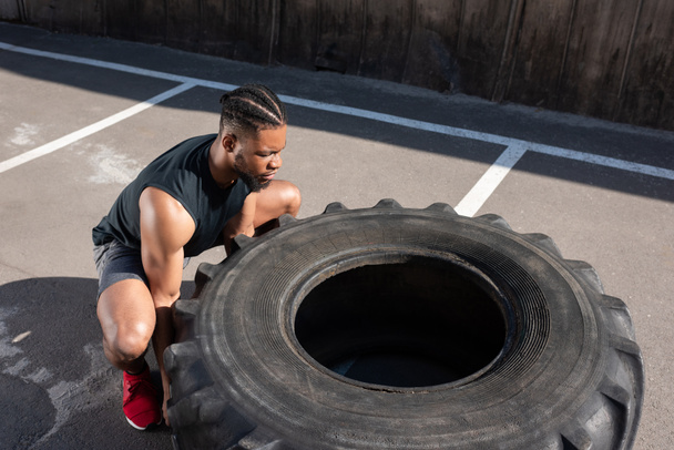 visão de alto ângulo do atleta afro-americano musculoso exercitando com pneu na rua
   - Foto, Imagem