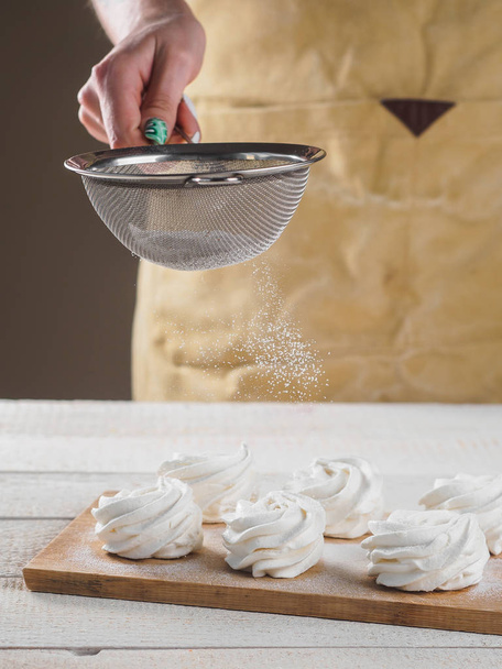 Zephyr blanc fait maison avec de la poudre de sucre à la main
. - Photo, image