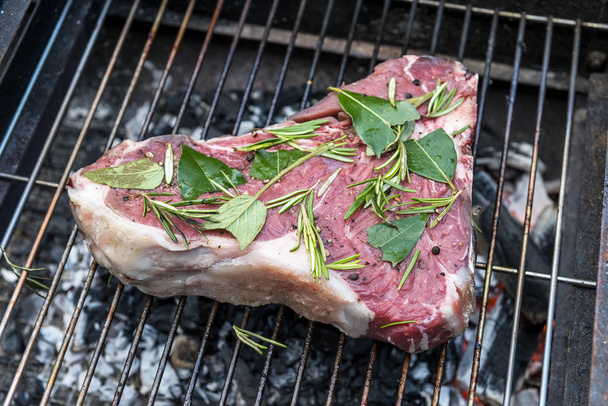 Ham T-Bone biftek pişirme ot ile ızgara üzerinde izole beyaz arka plan - Fotoğraf, Görsel