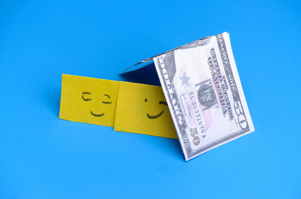 Souriants sourires jaunes dans la maison de l'argent. Le concept de prêts pour la famille
. - Photo, image