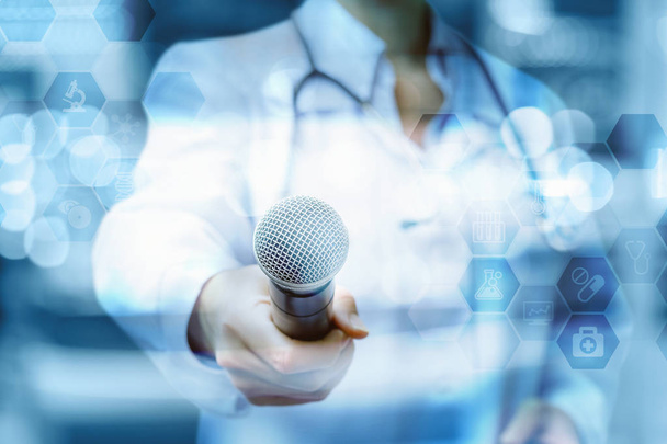 Doctor holds out the microphone on blurred background. - Photo, Image