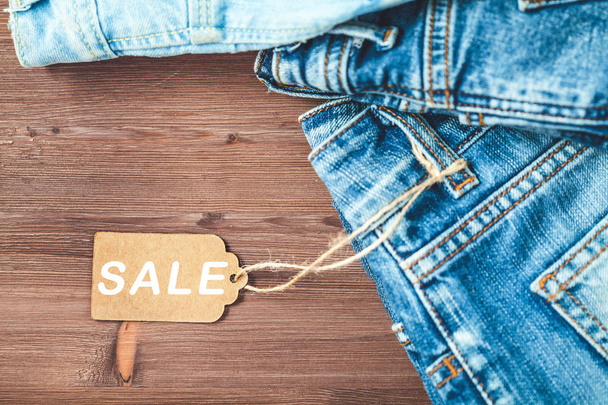 Concept sales, Black Friday discounts with tag, blue jeans on a wooden background Copyspace. Flat lay Top view. - Photo, Image