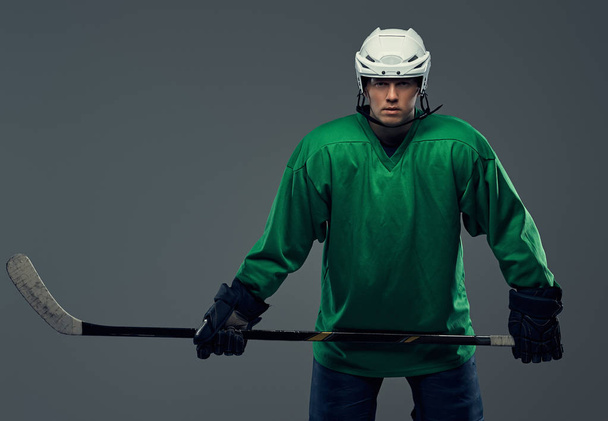 Portrét profesionální hokejista nosit výstroj a hokejky. Na šedém pozadí, samostatný. - Fotografie, Obrázek