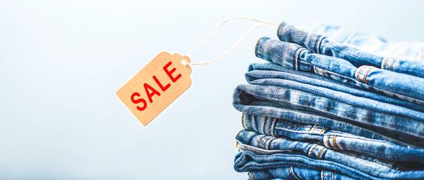 sale, discount, black Friday concept with tag , blue jeans on a light background. Copyspace Banner Red sale sings. - Zdjęcie, obraz
