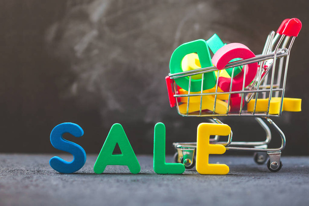 sale, discount, black Friday concept with bright inscription Sale on a dark background, consumer trolley with letters Close up. - Foto, Bild