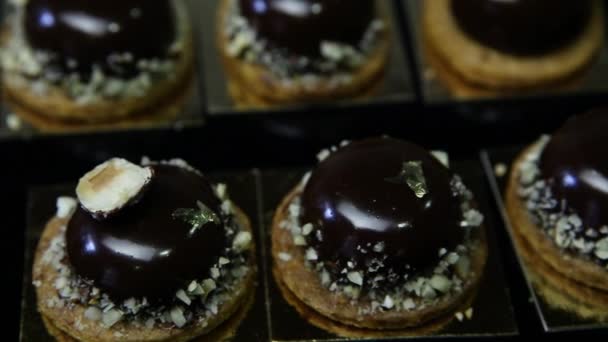 Nahaufnahme-Panorama auf kleinen runden Schokoladenptifur-Desserts stehen auf schwarzem Tisch - Filmmaterial, Video