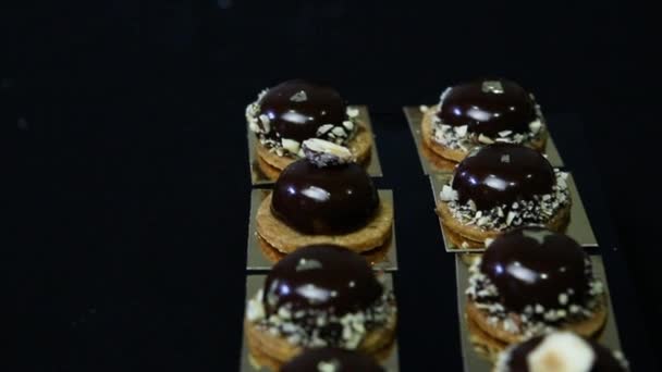Πανόραμα κάτω σε μικρά στρογγυλά γλυκά σοκολάτας περίπτερο στον μαύρο πίνακα - Πλάνα, βίντεο