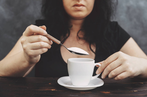 woman pouring sugar into coffee cup - Fotó, kép