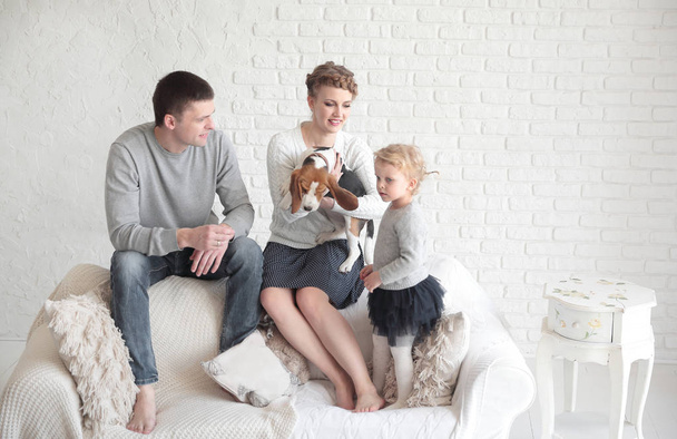 portrait of happy parents with their daughter and beloved pet with a living room - Fotografie, Obrázek