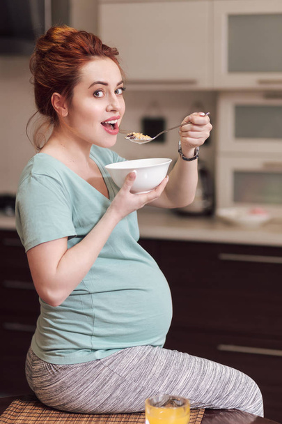 Szép terhes nő étkezési gabona  - Fotó, kép