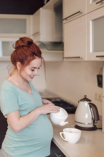 Smiling pregnant woman pouring tea - Zdjęcie, obraz
