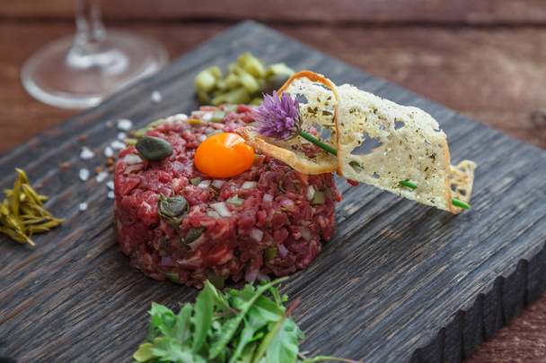Beef tartare with capers, pickled cucumber and fresh onions on dark background - Fotó, kép