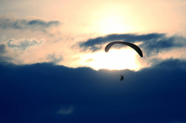Parapente voando em uma asa no céu contra o pôr do sol
 - Foto, Imagem