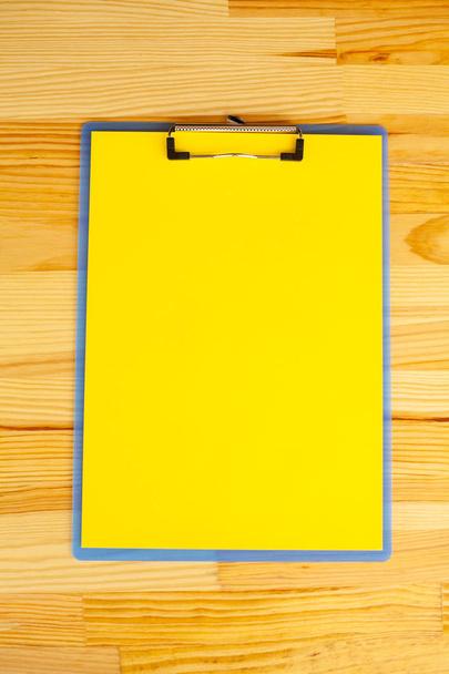 Mão de escritório Segurando uma pasta com um papel de cor amarela no fundo da mesa de madeira. Espaço de cópia. Lugar para texto
. - Foto, Imagem