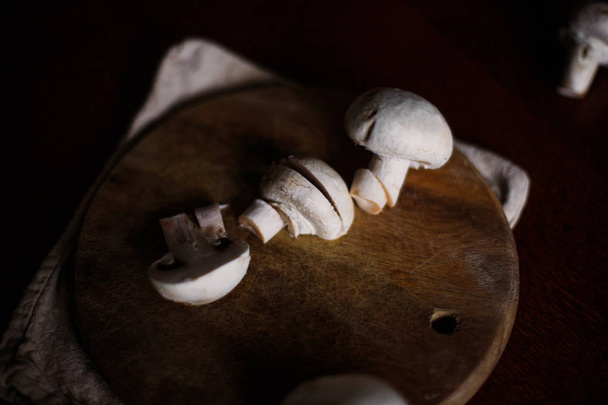 Mushrooms lie cut on a wooden board. White mushrooms, light from the window. - Photo, Image