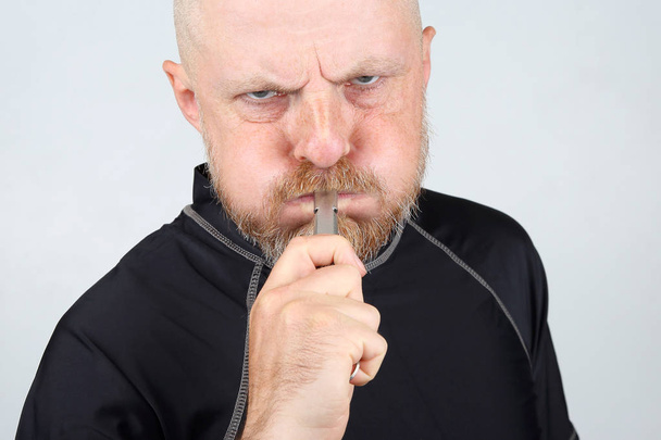 Vousatý muž v černém kabátku hvizdem píšťalky - Fotografie, Obrázek