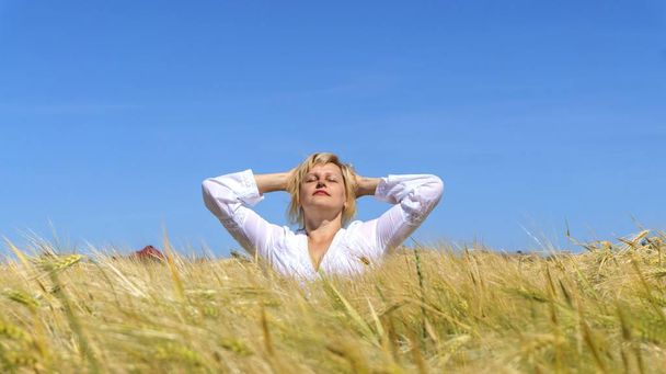 Frau meditiert. Meditation als Lebensform. Entspannung an der frischen Luft. Porträt der glücklichen schönen jungen Frau. im Weizenfeld  - Foto, Bild