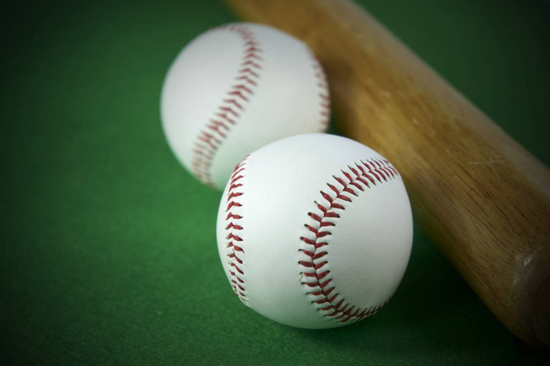 Два белых бейсбольных мяча и деревянная летучая мышь изолированы на зеленом фоне
 - Фото, изображение