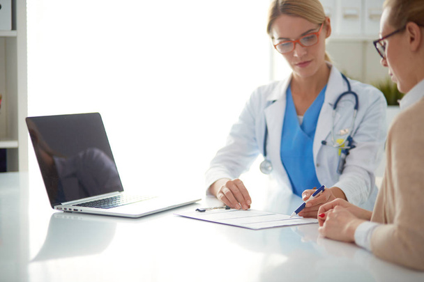 Doctor and patient couple are discussing something,sitting on the desk. - Photo, Image