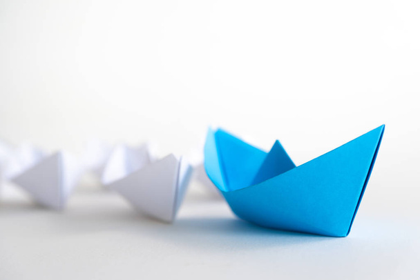 リーダーシップの概念。白の中で青紙船リード。リーダーの船が他の船をリードします。. - 写真・画像