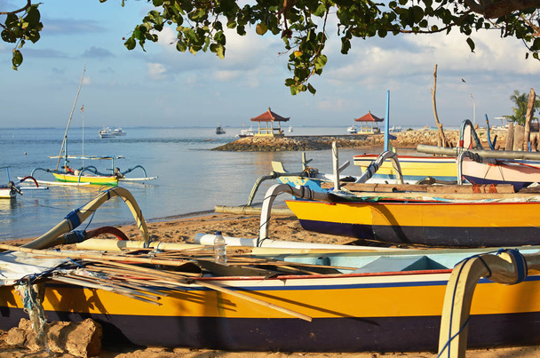 Рыбацкие лодки и оборудование, отдыхающие на пляже Санур, Индонезия на рассвете
. - Фото, изображение