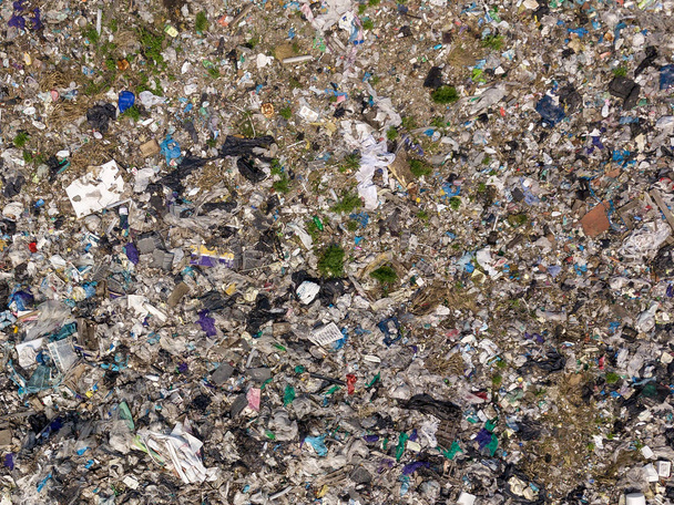Environmental pollution. Aerial top view photo from flying drone of large garbage pile. Garbage pile in trash dump or landfill near the green forest. - Photo, Image