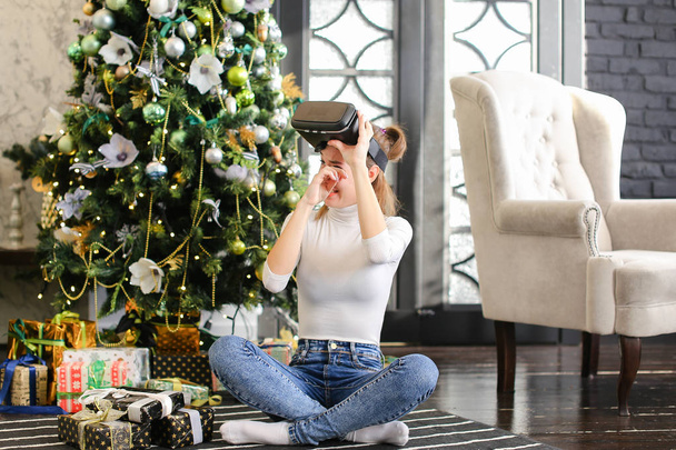 sister testing virtual reality glasses near New Year tree.  - Фото, изображение